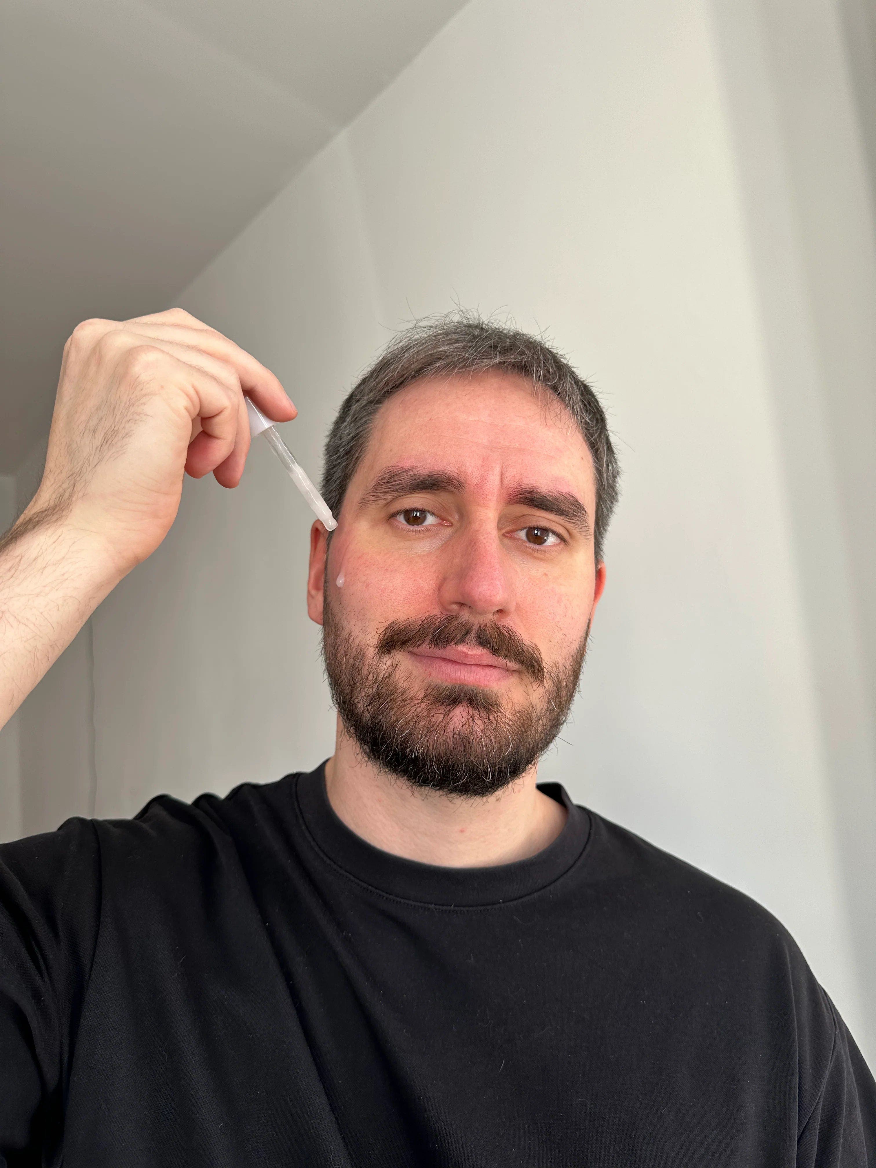 Ein Mann trägt ein Serum von Rosental Organics auf sein Gesicht auf.